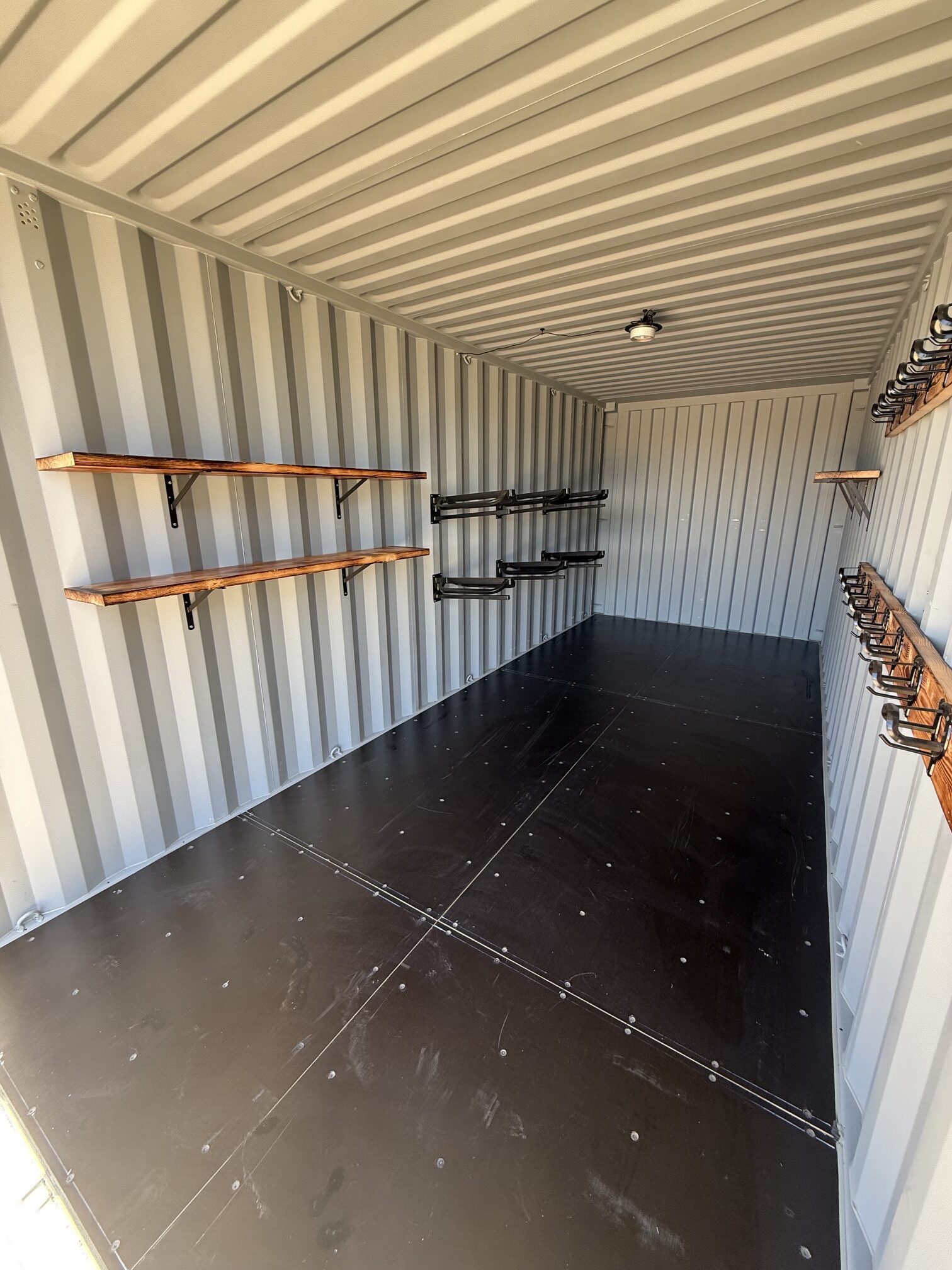 Interior of a 20-foot container tack shed by Conex Creation & Supply with saddle racks, shelving, bridle hooks, and open storage space for ranch and horse property use in Southern Arizona.