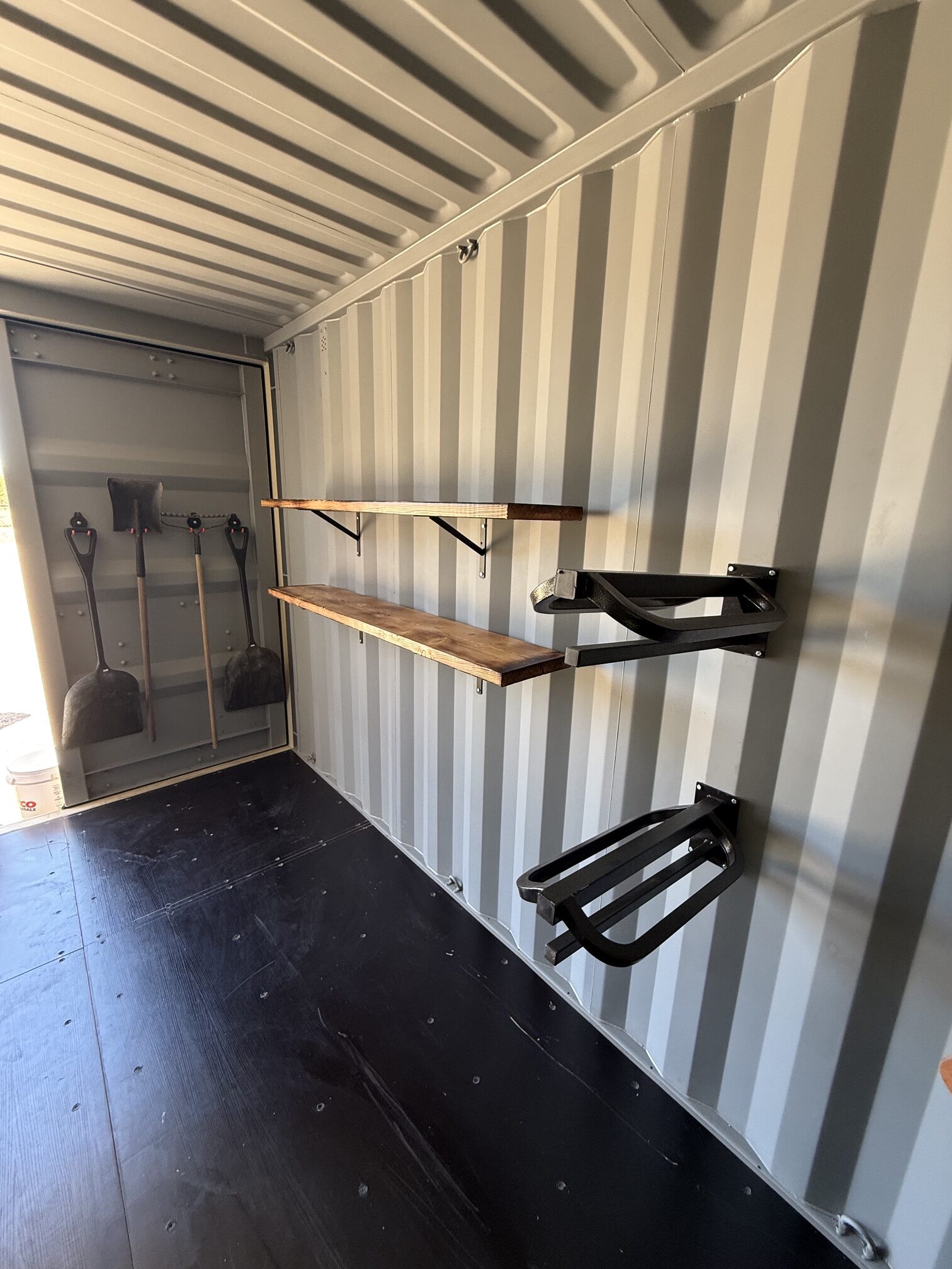 Interior of a 20-foot custom container tack shed by Conex Creation & Supply showing saddle racks, wall shelving, and tool hooks for ranch and horse property storage in Southern Arizona.