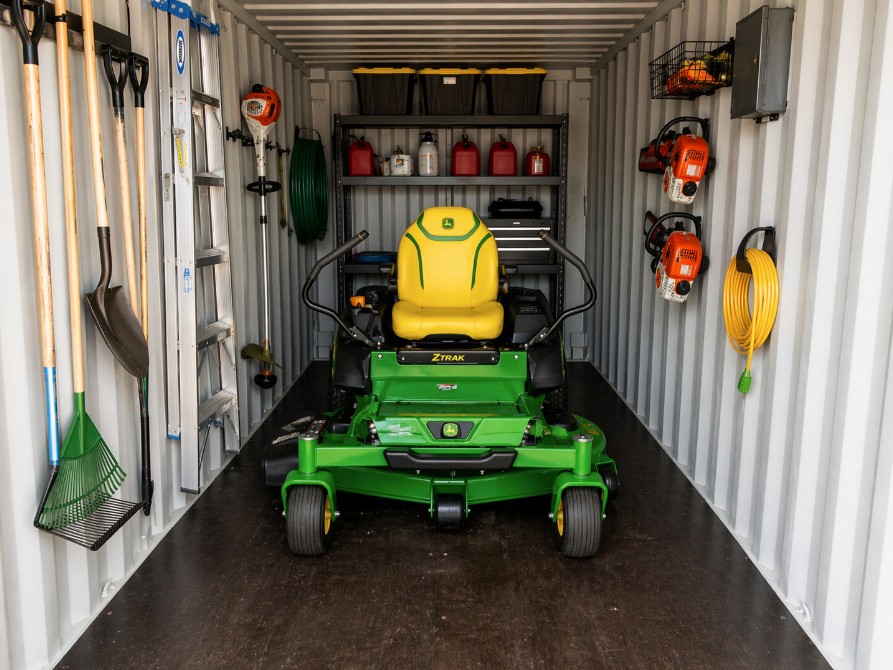 Zero-turn mower and lawn tools stored inside a rented 20-foot shipping container in Southern Arizona.